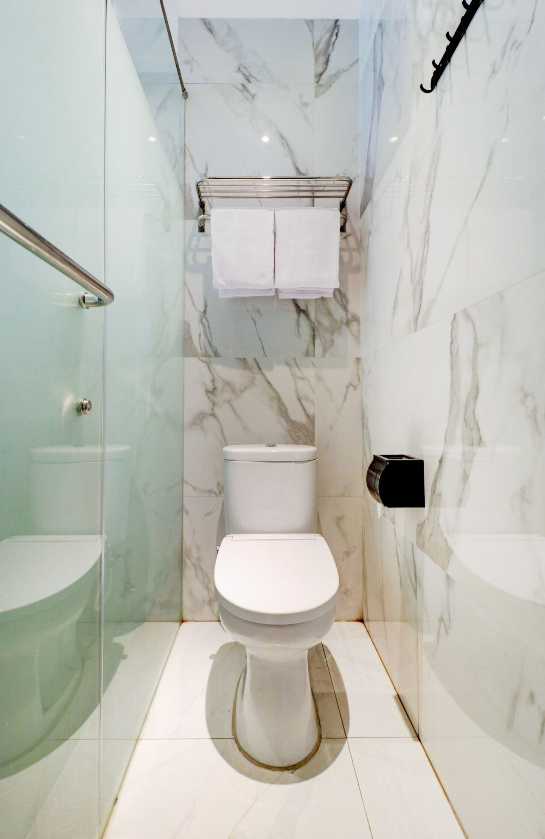 A modern bathroom with a glass-enclosed shower, a white toilet, and a marble backsplash.