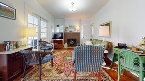 A living room with a fireplace, a television, and a green chair. - FT Away From Lake MI Beaches Golf Tennis Park Trails & More Dog Friendly New AC (New Buffalo)