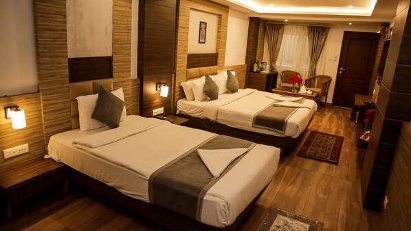 Habitación de hotel con dos camas, paneles de madera, una mesita de noche con lámpara, una silla y una ventana con cortinas.
