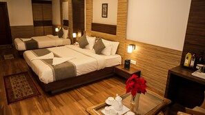 A hotel room with two beds, a bedside table with a tray of tea and a vase of red flowers, and a wooden floor. - Cocoon By Morpho Rain Lily Green Park (Darjeeling)