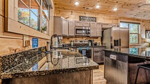 A modern kitchen with granite countertops, stainless steel appliances, and wooden cabinetry. - Moonrise Ridge Cabin in Sevierville – Sleeps 12 • Views • Hot Tub • Game Loft (Sevierville)