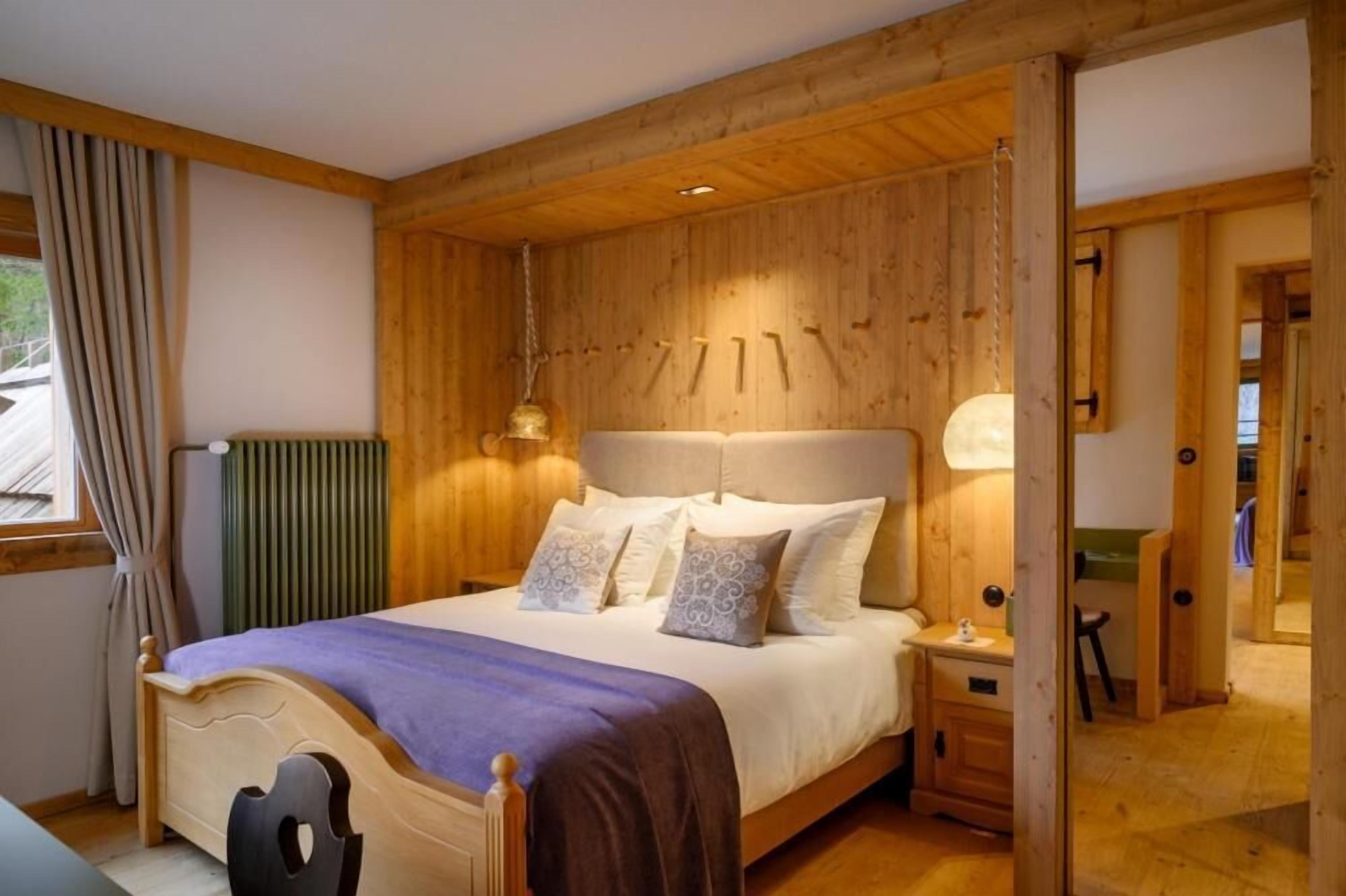Un dormitorio con paneles de madera, una cama, una mesita de noche y vistas a un espacio exterior verde.