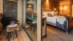 A cozy bedroom with a bed, bedside table, and a chair. - Boutique Hotel Vila Planinka (Jezersko)