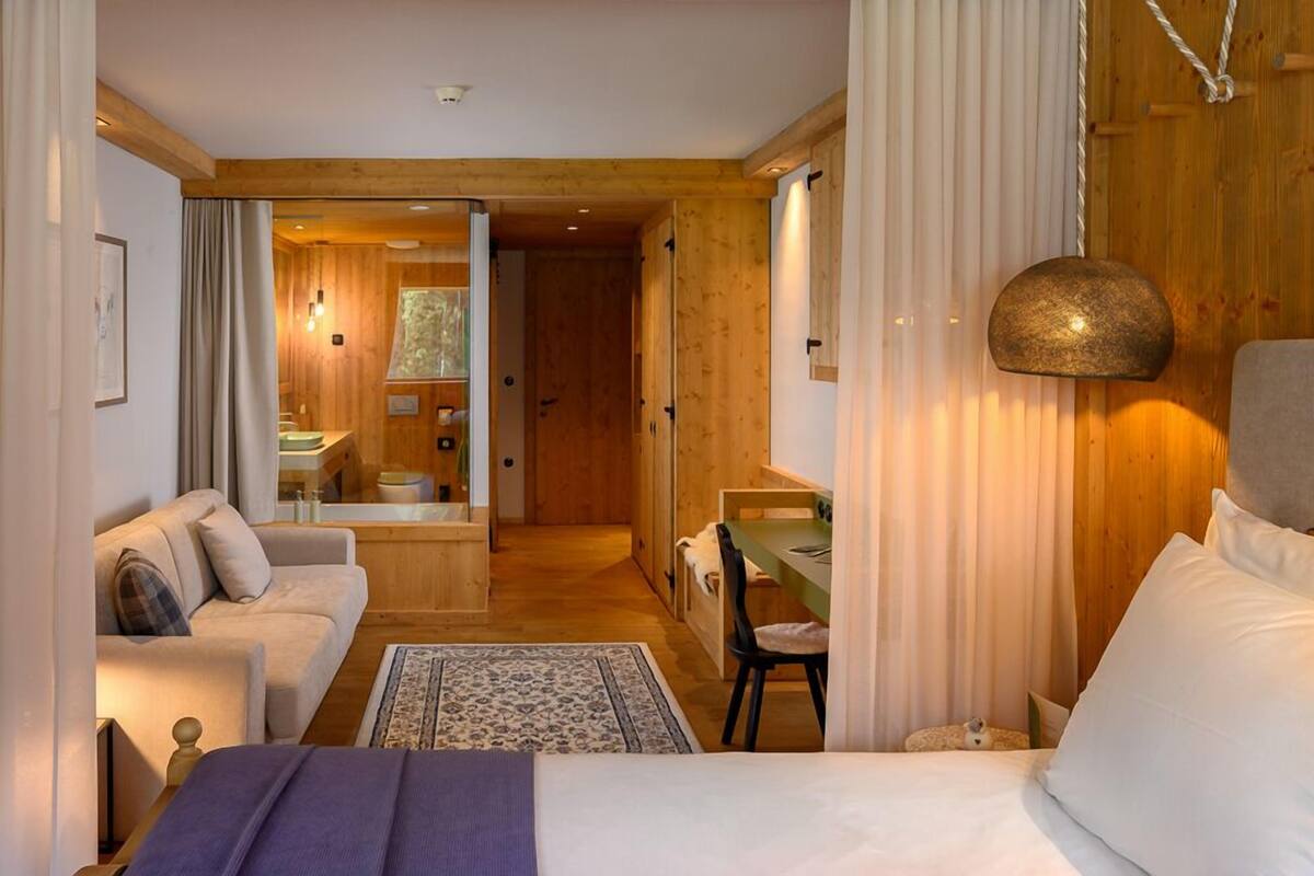 A cozy room with a bed, a sofa, a dining table, and a small kitchen area.