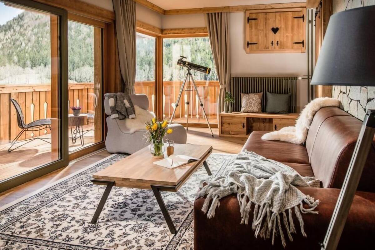 A cozy living room with a wooden floor, a sofa, a coffee table, and a telescope.