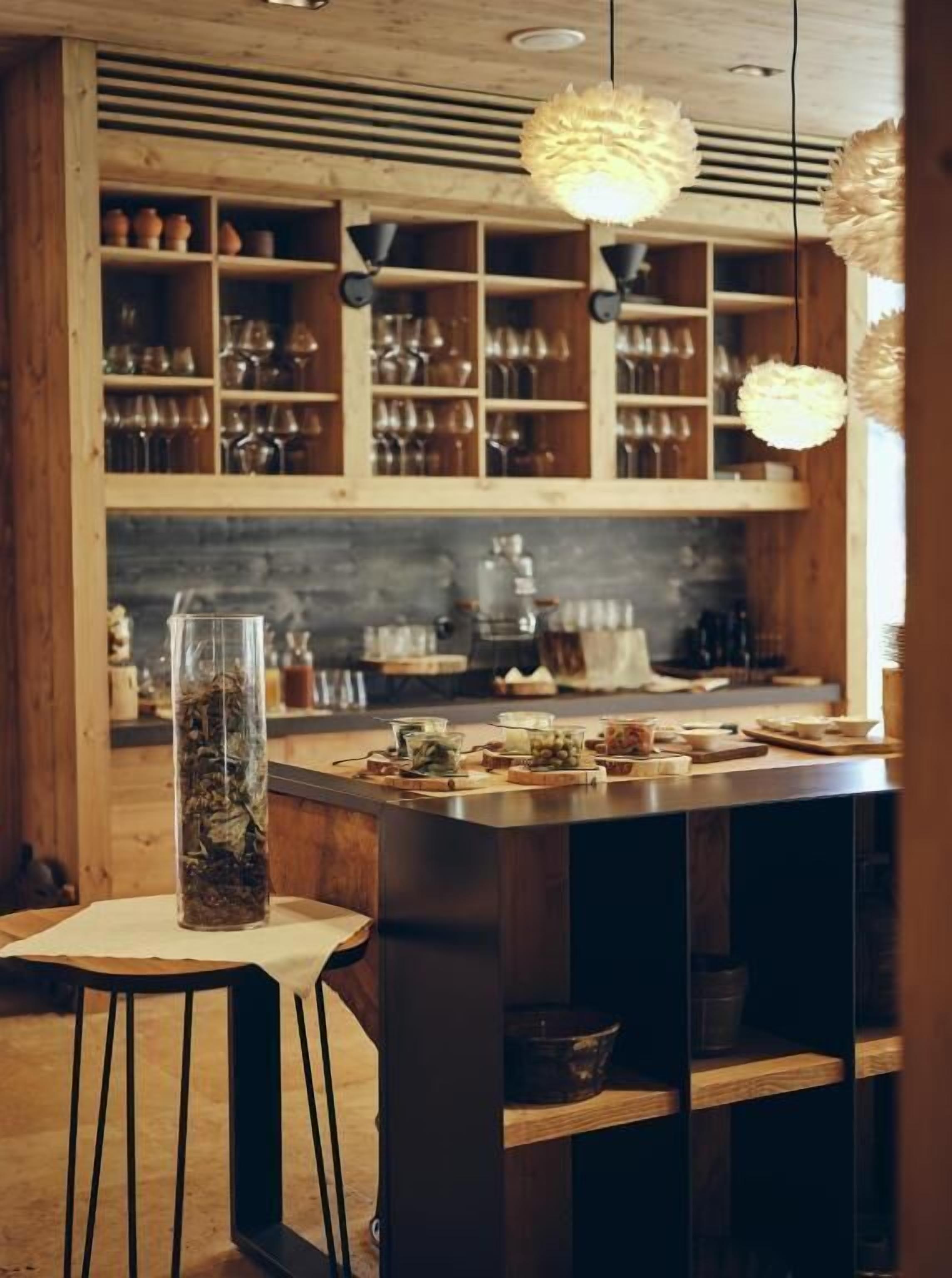 A kitchen with wooden shelves, a central island, and hanging lights.