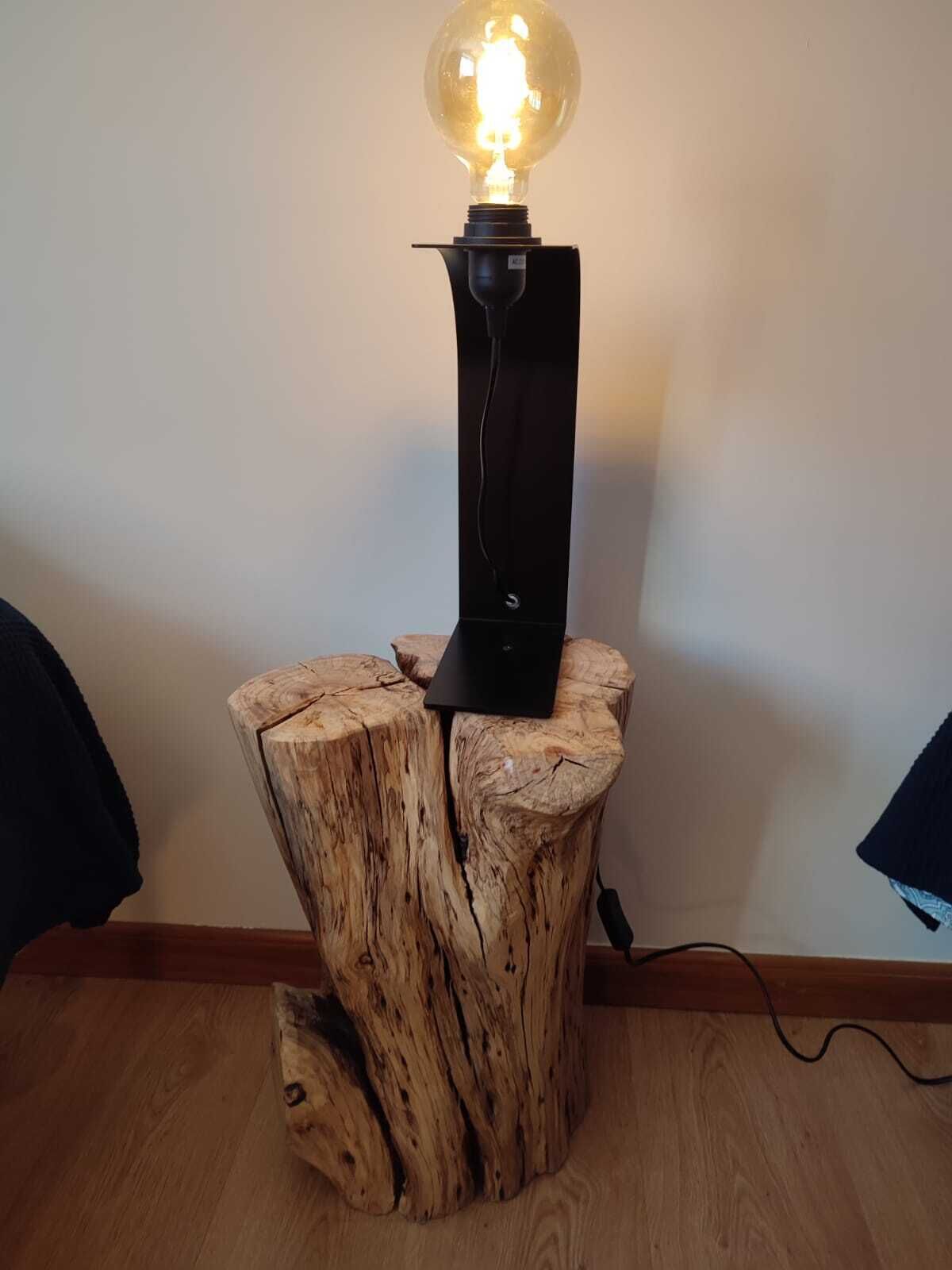A table lamp with a glass bulb on a wooden stump base.