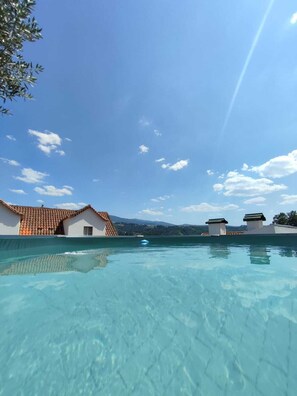A clear swimming pool with a view of buildings and mountains in the background. - Secrets of the Mountains - Seia (Seia)