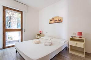 Une chambre à coucher comprenant un lit, deux tables de chevet, une commode, une fenêtre et une œuvre d’art accrochée au mur.