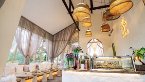 Une pièce chaleureuse avec un canap é, une table surmontée d’une vitrine, et de grandes fenêtres dotées de rideaux.