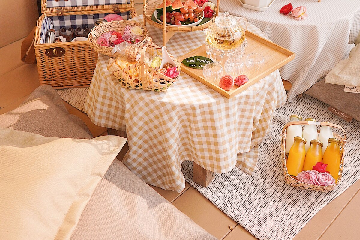 A cozy dining setup with checkered tablecloths, wicker baskets, and tiered serving trays filled with food and drinks.