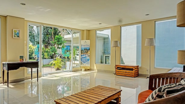 A spacious room with a piano, a wooden bench, a sofa, and a view of a pool through glass doors. - Collection O 91288 Chrysant Premiere Residence (Malang)