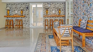A lobby with a polished tile floor, wooden furniture, and patterned walls. - Collection O 91288 Chrysant Premiere Residence (Malang)