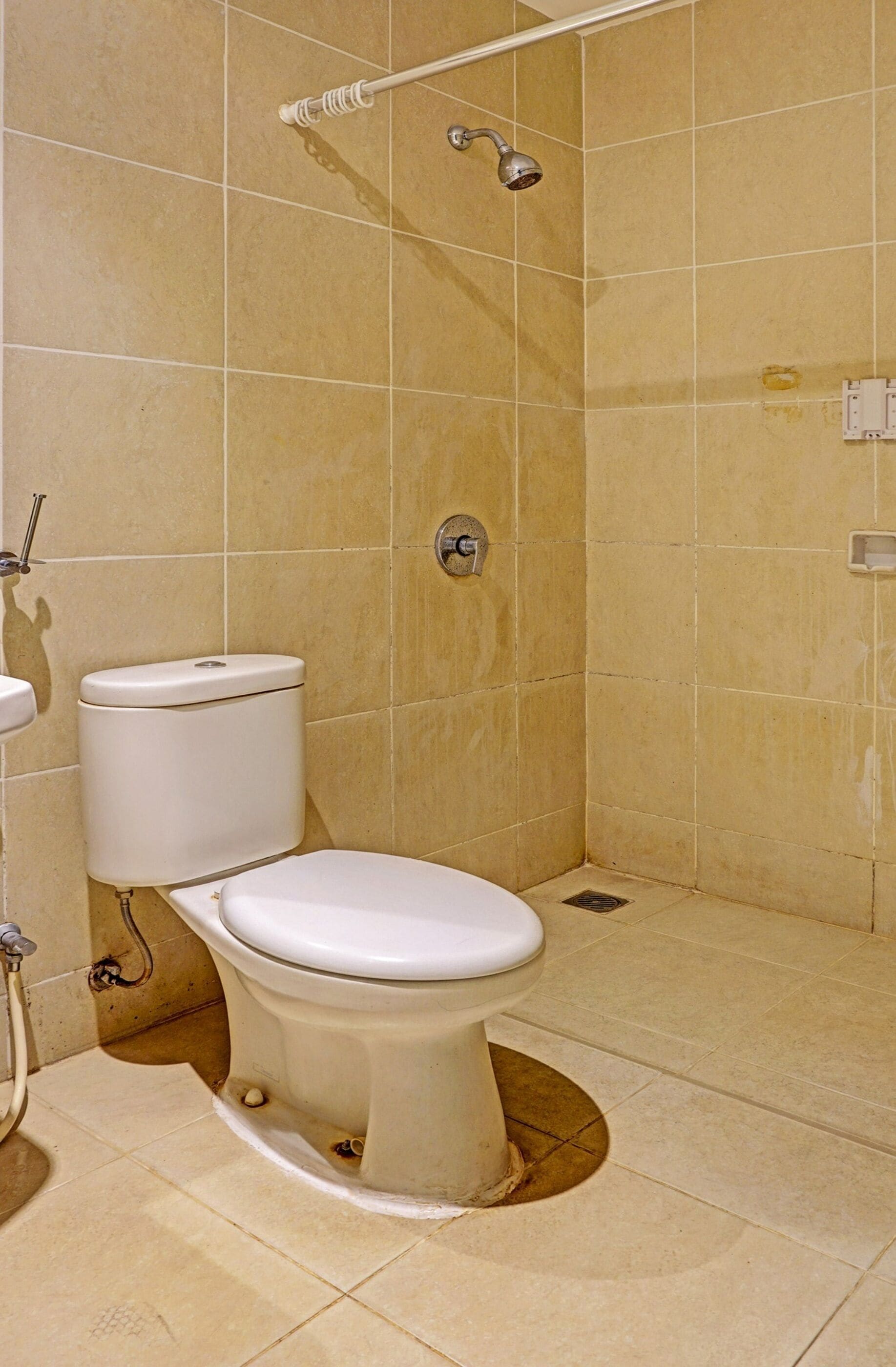 Une salle de bain avec des toilettes, une douche et des murs carrelés.