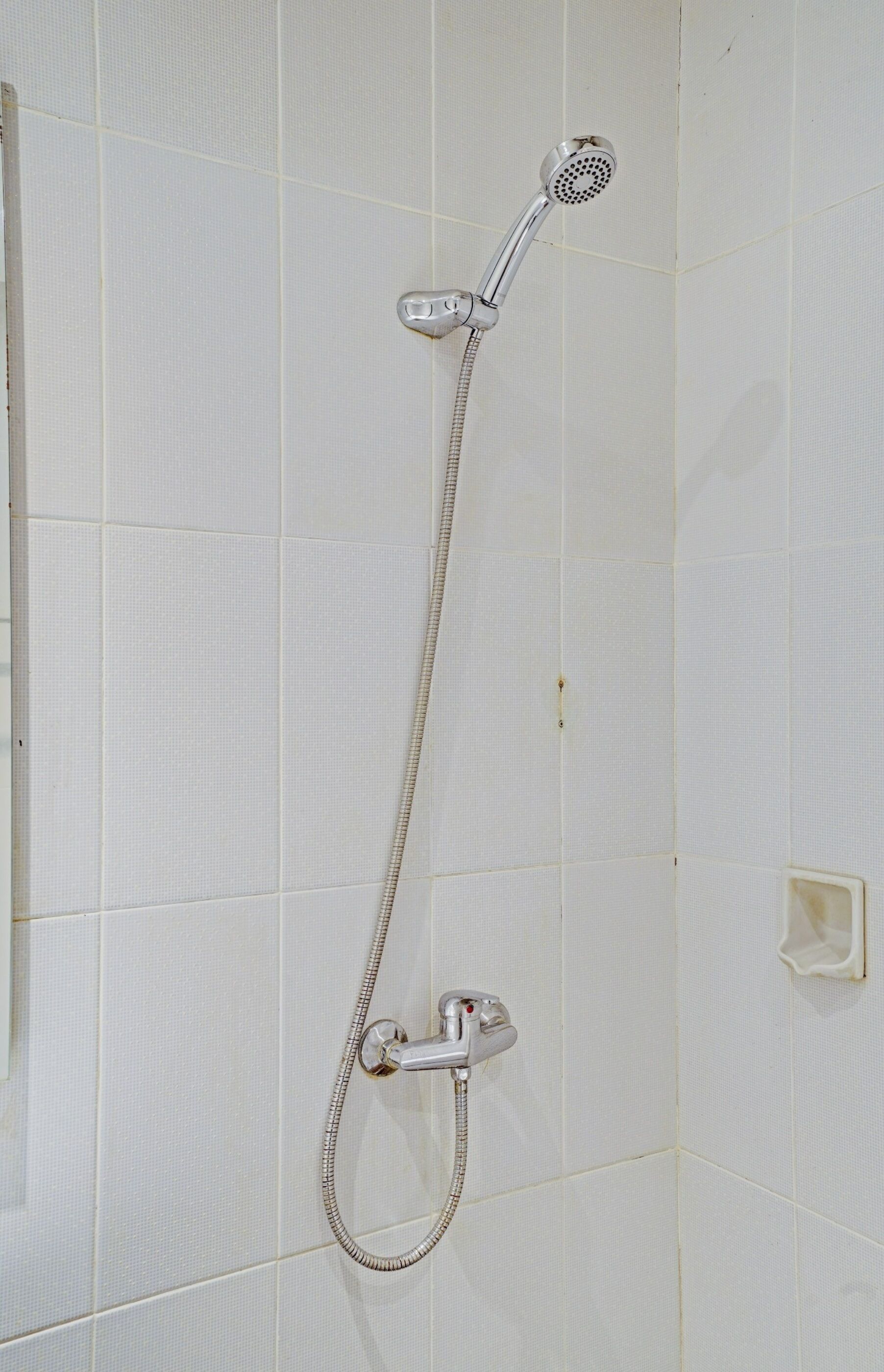 A shower with a handheld showerhead and a handheld hose.