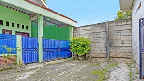 Een binnenplaats met een blauwe poort, een groene muur en een betonnen muur.