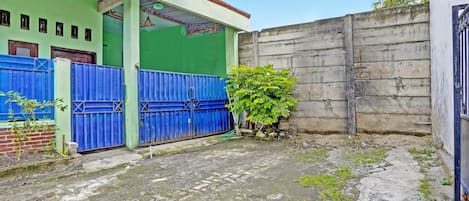 A courtyard with a blue gate, a green wall, and a concrete wall.