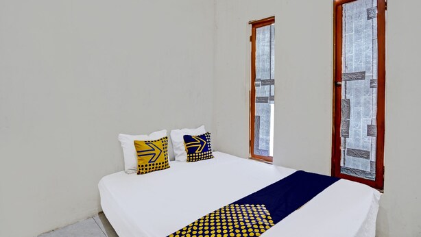 Een slaapkamer met een groot bed, twee ramen en uitzicht op de stad.
