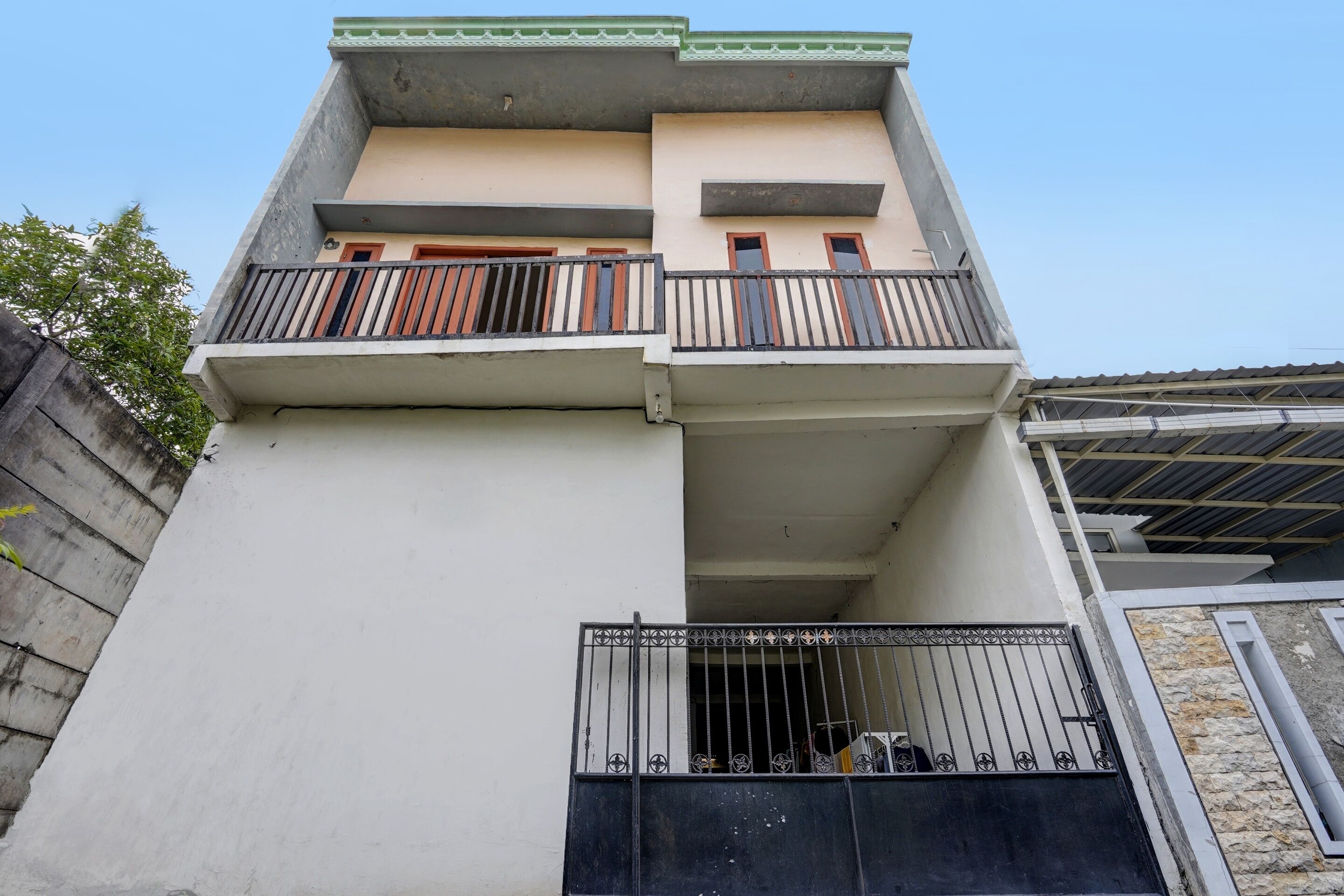 A multi-story building with balconies, a gated entrance, and a stone facade.