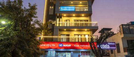 A modern hotel with a Kotak Mahindra Bank sign, multiple floors, and a Kotak Mahindra Bank ATM on the ground floor.