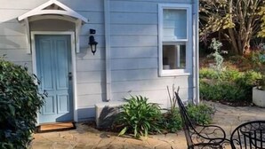 Une maison avec une porte bleu clair, une petite fenêtre et un porche avec une chaise.