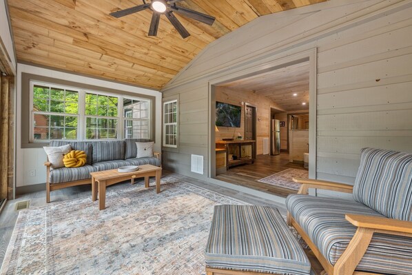 A cozy living room with a wooden ceiling, a sofa, a coffee table, and a patterned rug. - The River's Edge (Blue Ridge)