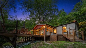 A wooden cabin with a glass extension, a wooden deck, and a stone pathway. - The River's Edge (Blue Ridge)