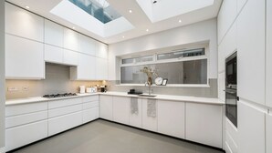 A modern kitchen with white cabinetry, a skylight, and a built-in oven. - City Centre - Townhouse - Stay 10 - Cinema Room (London)