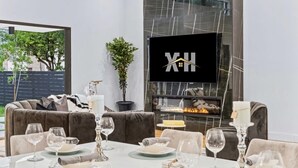 A modern living room with a fireplace, a sofa, and a dining area set for a meal.