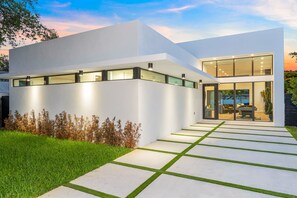 Een modern huis met een plat dak, grote ramen en een goed verlichte gevel.