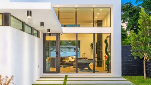 A modern house with a glass door leading to a living area with a pool table.