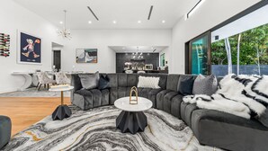 A modern living room with a sectional sofa, a round coffee table, and a marble-patterned rug.
