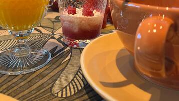 Une table avec un verre de jus d’orange, un verre de fruits rouges mélangés et un bol de soupe.
