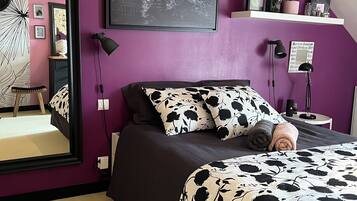Una camera da letto con un letto grande, una mappa del mondo appesa al muro, uno specchio e uno scaffale con oggetti decorativi.