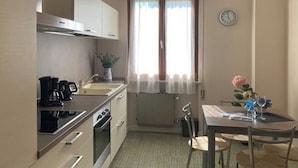 A compact kitchen with a stove, sink, and a dining area with a table and chairs.