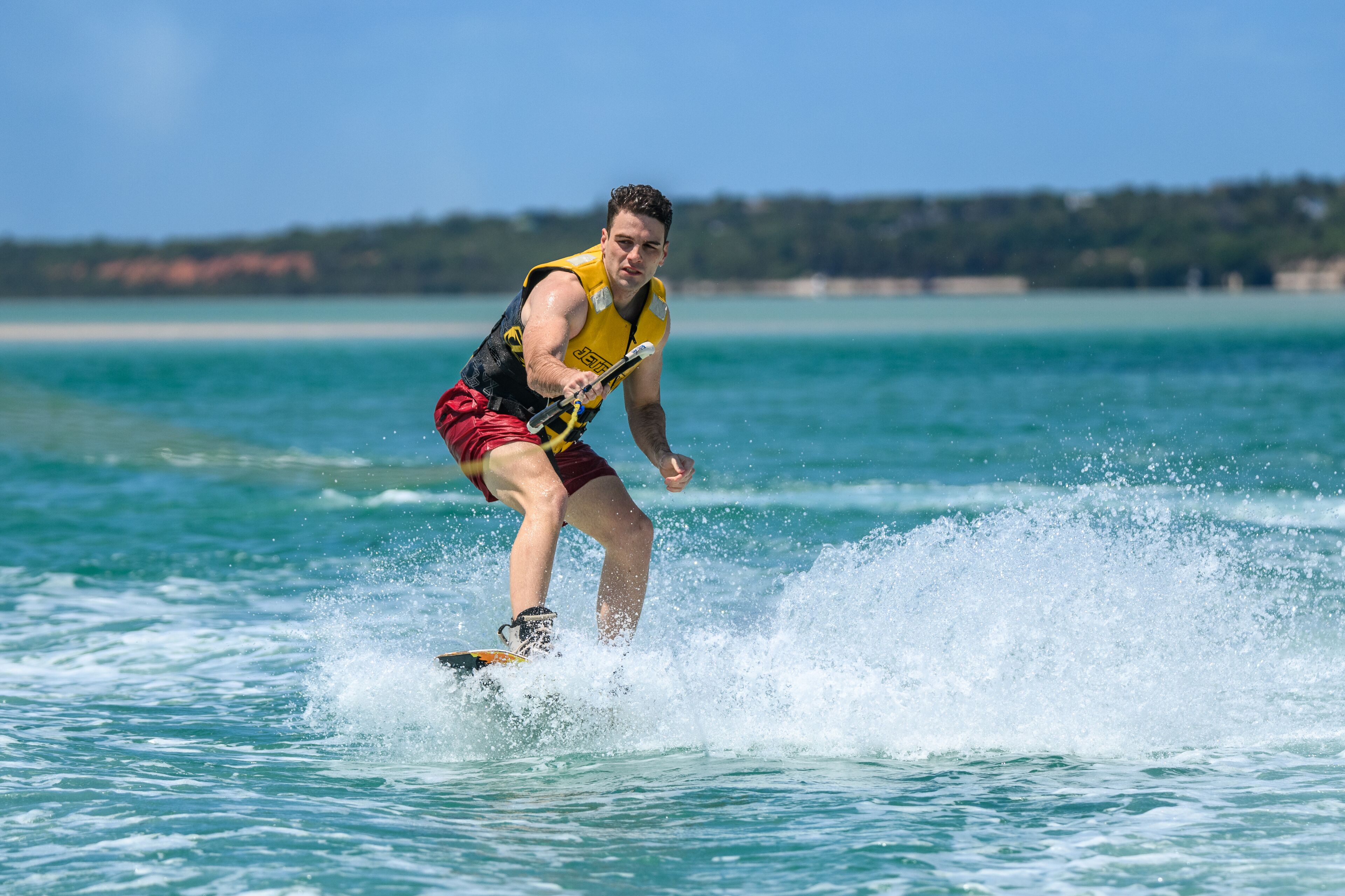 Eine Person treibt auf einem Wakeboard über das Wasser.