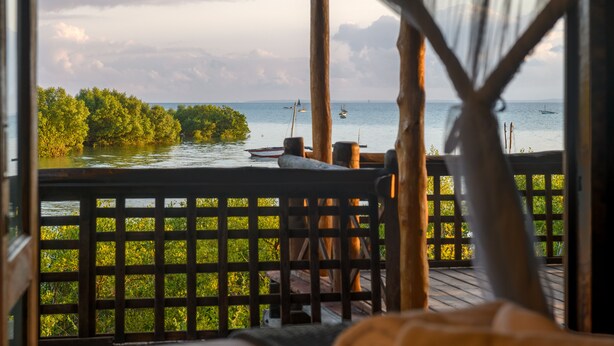 A wooden deck with a view of the sea and a thatched roof structure. - Ocean Pearl Beach Lodge (Vilanculos)