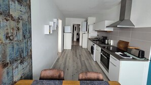 Ett modernt kök med tvättmaskin, ugn och en matplats med bord och stolar.