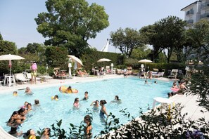 A swimming pool area with lounge chairs and umbrellas. - Family Hotel Alexander (Jesolo)