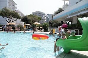 A swimming pool with people, lounge chairs, and umbrellas. - Family Hotel Alexander (Jesolo)