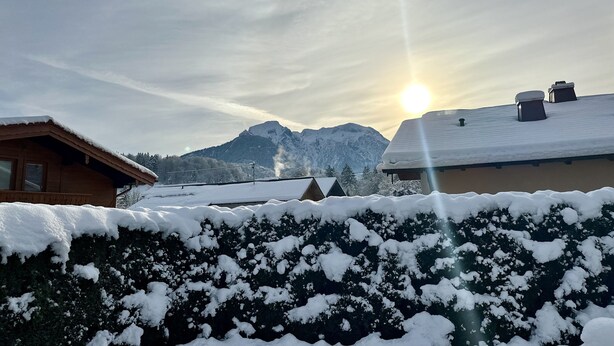 A snowy landscape with a mountain in the background and a building with a snow-covered roof.