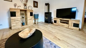 A modern living room with a wooden floor, a black coffee table, a TV, and a fireplace.