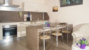 Eine moderne Küche mit einer zentralen Kochinsel, Edelstahlgeräten und einem Essbereich mit Stühlen und einem Tisch.