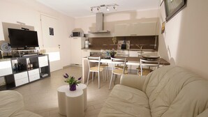 Ein modernes Wohnzimmer mit einem beigen Sofa, einem Flachbildfernseher und einem kleinen Beistelltisch mit einer Vase.