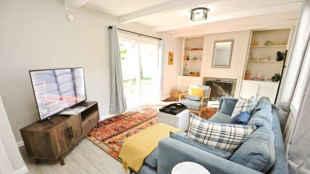 Ett vardagsrum med en soffa, en tv, ett soffbord och en mönstrad matta.