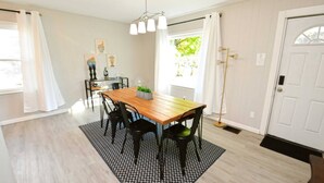 Een eetruimte met een houten tafel, zwarte stoelen, een kamerbreed tapijt en een hanglamp.