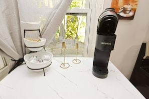 Eine Küchenarbeitsfläche mit Kaffeemaschine, einem Tellergestell und einem Fenster mit Blick auf Grünflächen.