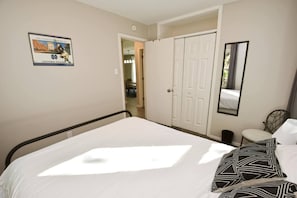 Une chambre à coucher avec un lit, une armoire, un miroir et un tableau encadré accroché au mur.