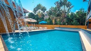 A swimming pool with clear blue water, surrounded by lounge chairs and umbrellas. - Brisa do Caita Praia Hotel (Cairu)