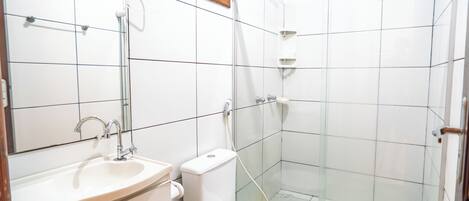 Un baño con lavamanos, inodoro y zona de ducha con mampara de vidrio.